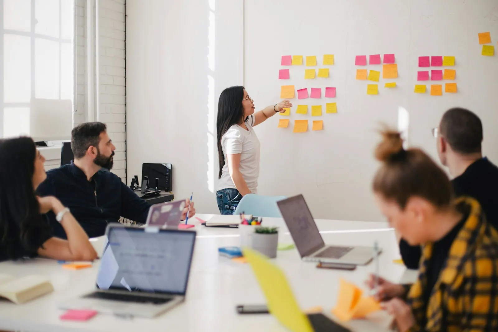 Equipe em sessão de planejamento, mapeando etapas de um processo com post-its em uma parede.